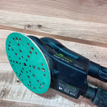 Green aluminum oxide multi-hole sanding disc fitted to a Festool ETS EC 150 sander on a wood surface