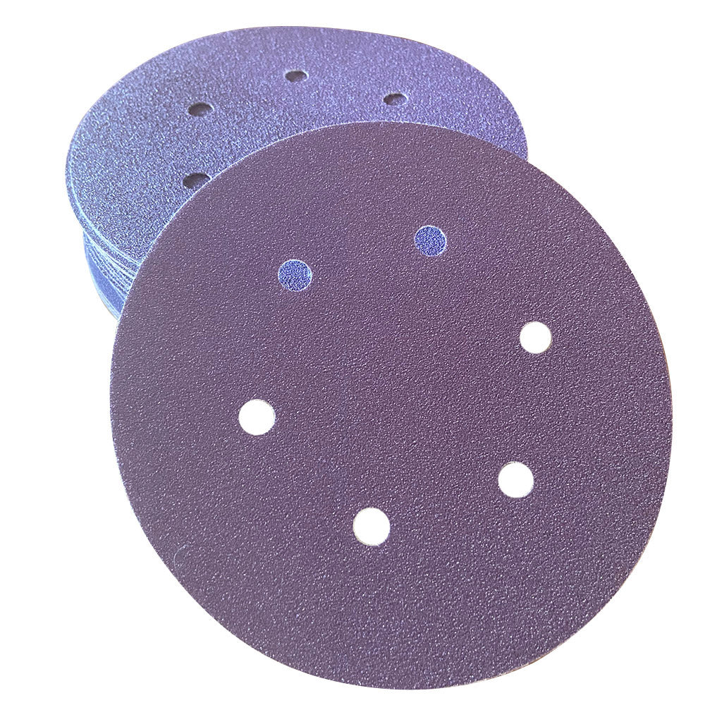 Stack of purple ceramic 6 inch 6-hole sanding discs with one disc face up showing the abrasive grain